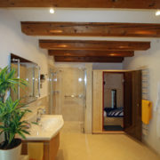 Holzbalken und elegante Lichttechnik geben den Bad einen besonderen Flair