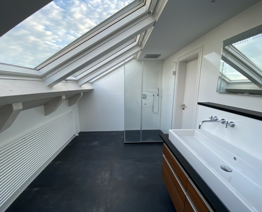 Helles Bad im Dach mit großen Fenster und angepasster Regendusche und großzügiges Waschbecken